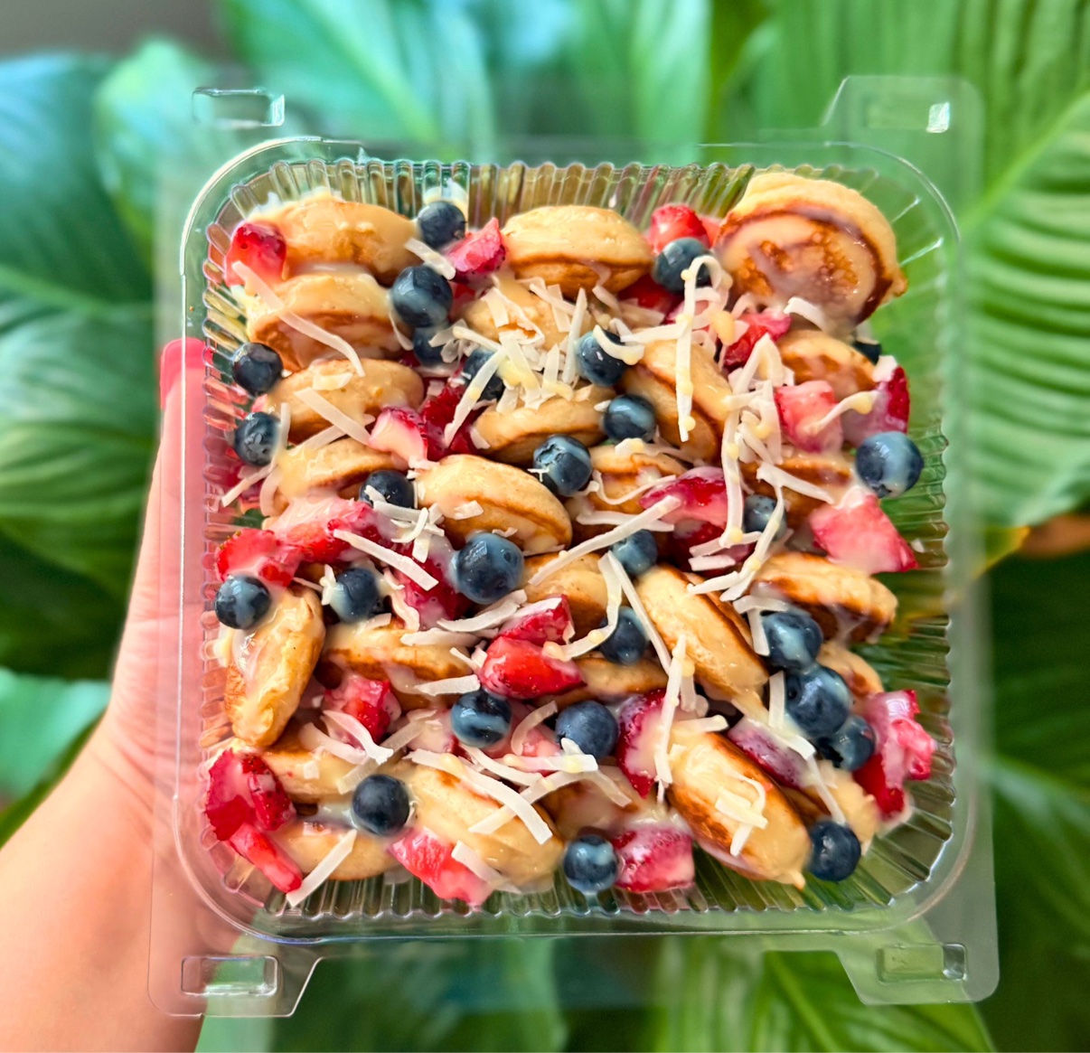 Mini pancakes topped with strawberries, blueberries, coconut and sweet cream